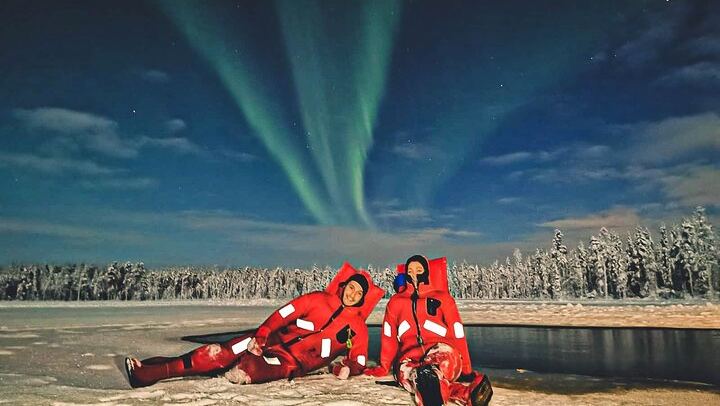 Eine kleine Gruppe von Menschen beobachtet treibendes arktisches Eis unter dem Polarlicht in Rovaniemi (2/12)