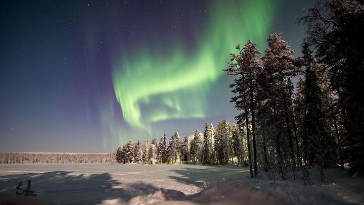 Eine kleine Gruppe von Menschen beobachtet treibendes arktisches Eis unter dem Polarlicht in Rovaniemi (4/12)