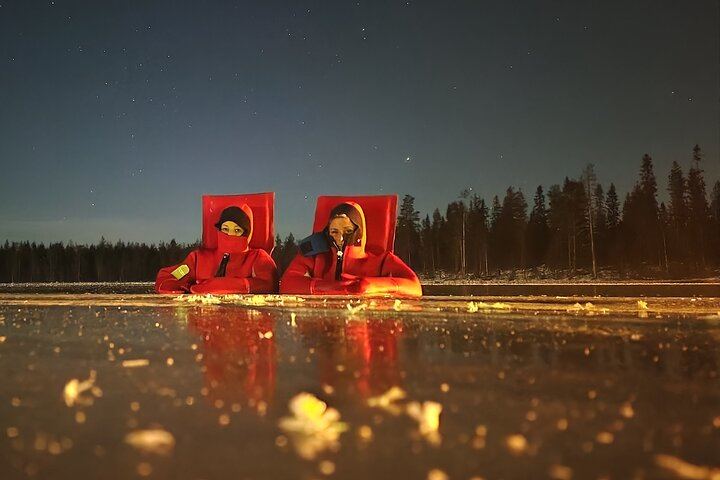 Eine kleine Gruppe von Menschen beobachtet treibendes arktisches Eis unter dem Polarlicht in Rovaniemi (1/12)