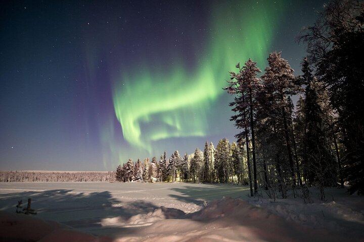 Eine kleine Gruppe von Menschen beobachtet treibendes arktisches Eis unter dem Polarlicht in Rovaniemi (4/12)