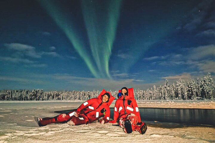 Eine kleine Gruppe von Menschen beobachtet treibendes arktisches Eis unter dem Polarlicht in Rovaniemi (2/12)