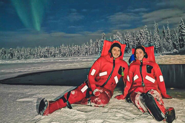 Eine kleine Gruppe von Menschen beobachtet treibendes arktisches Eis unter dem Polarlicht in Rovaniemi (12/12)