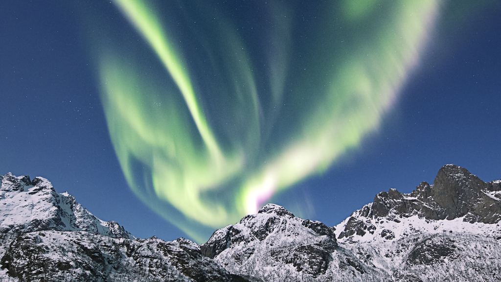 Bands of green aurora across a dark sky above a frozen northern landscape