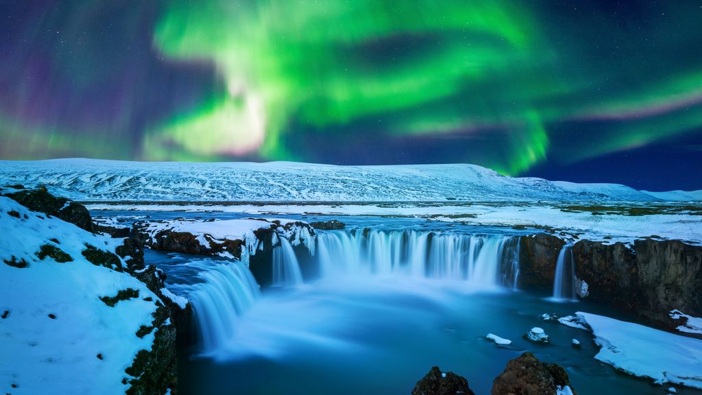 A wide waterfall in a snow-covered Icelandic landscape