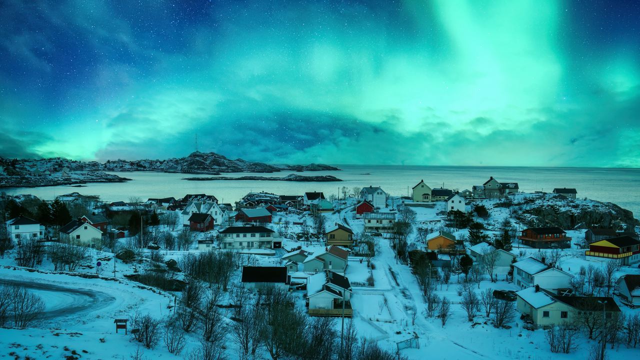 Green aurora over the snow covered houses of Moskenes village and the sea, Lofoten islands, Norway