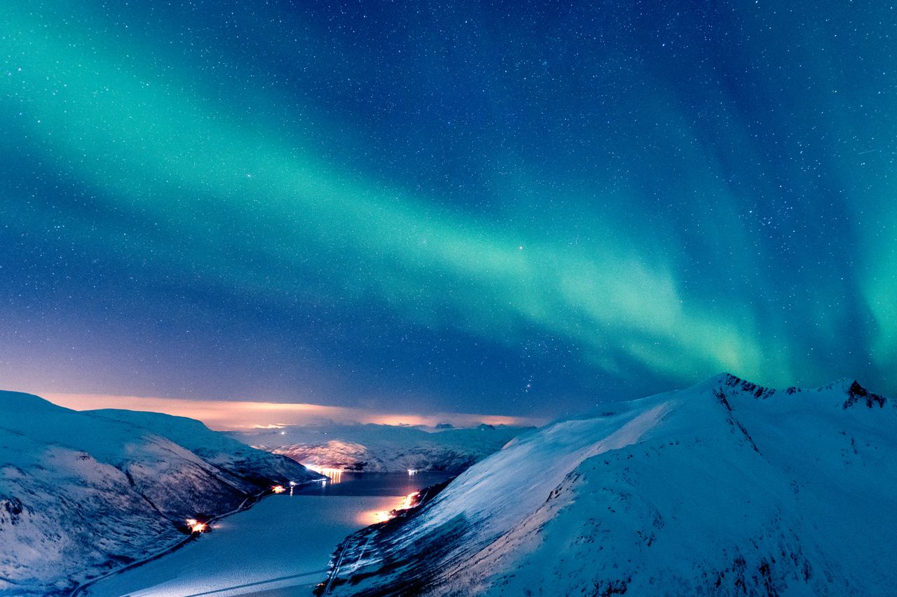 Aurora reflected in the still water of a frozen lake near Tromso, northern Norway