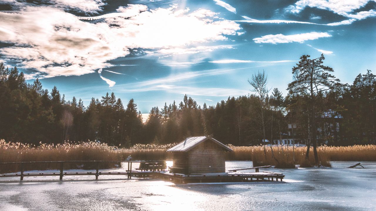 A small wooden hut standing on the ice of a frozen lake in winter