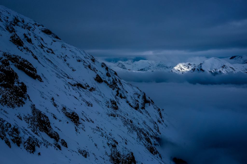 Heavy cloud covers the night sky above snow-covered hills, with no aurora visible