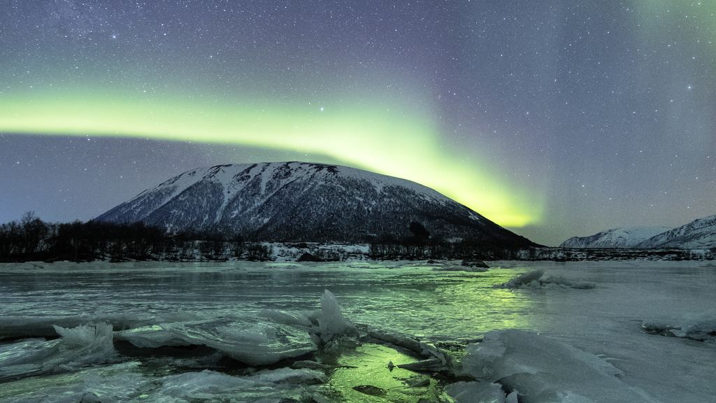 Aurora over snow-covered mountains in northern Norway