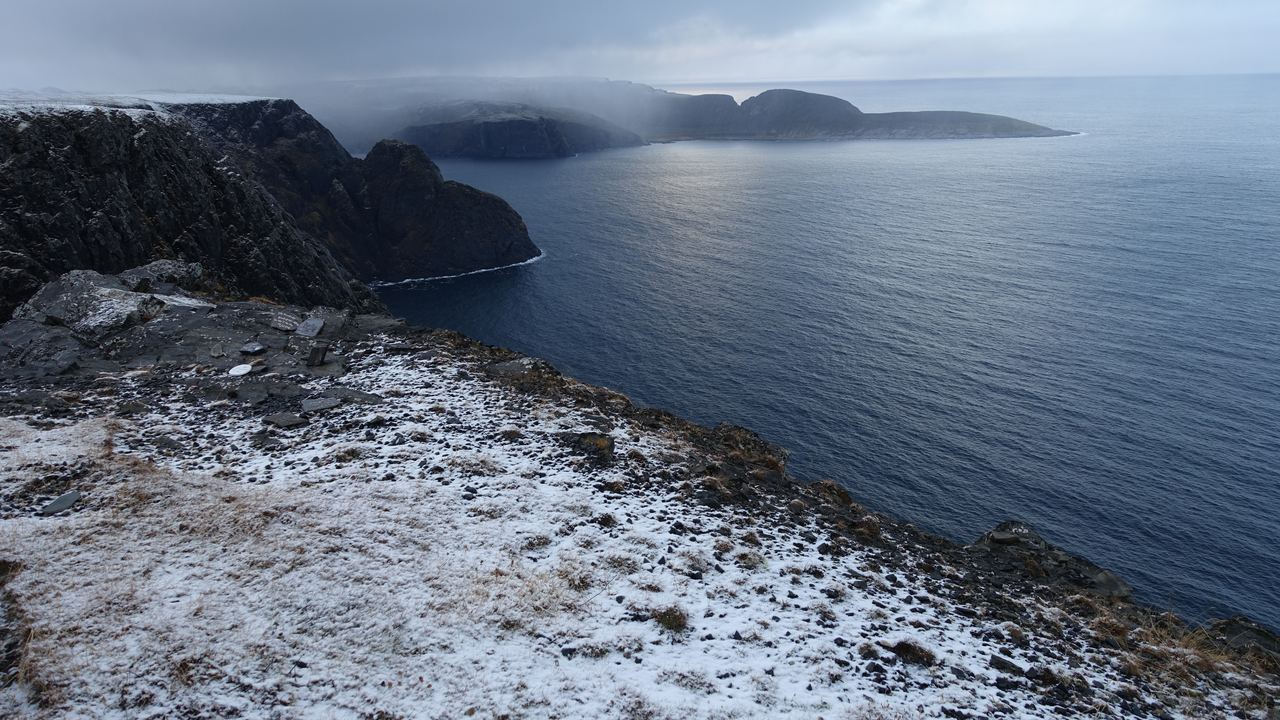 Misty snow covered cliffs dropping into the sea on the coast of northern Norway