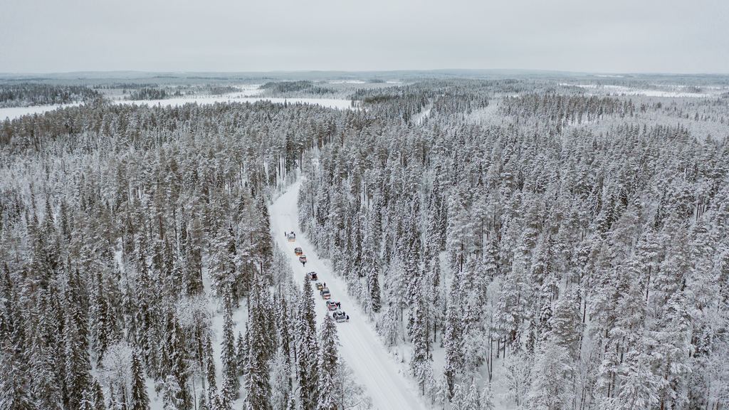 Cars driving along a snow-covered road through winter forest in Finland