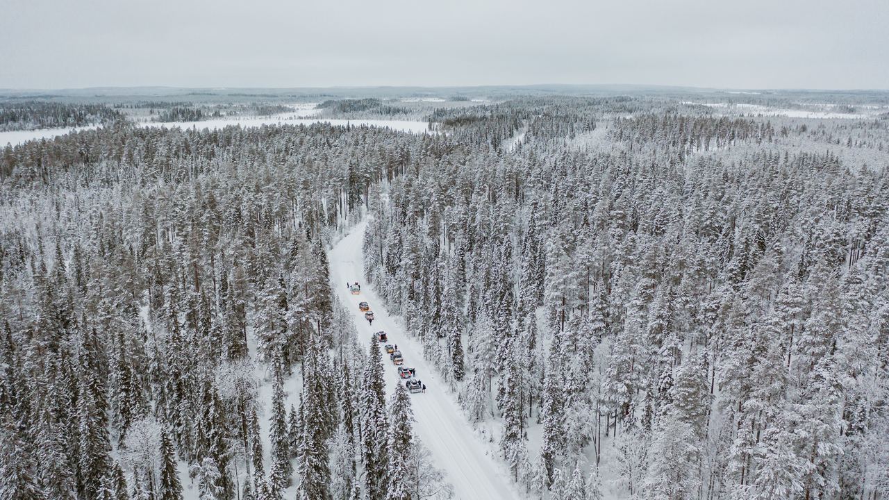 Cars driving along a snow-covered road through winter forest in Finland